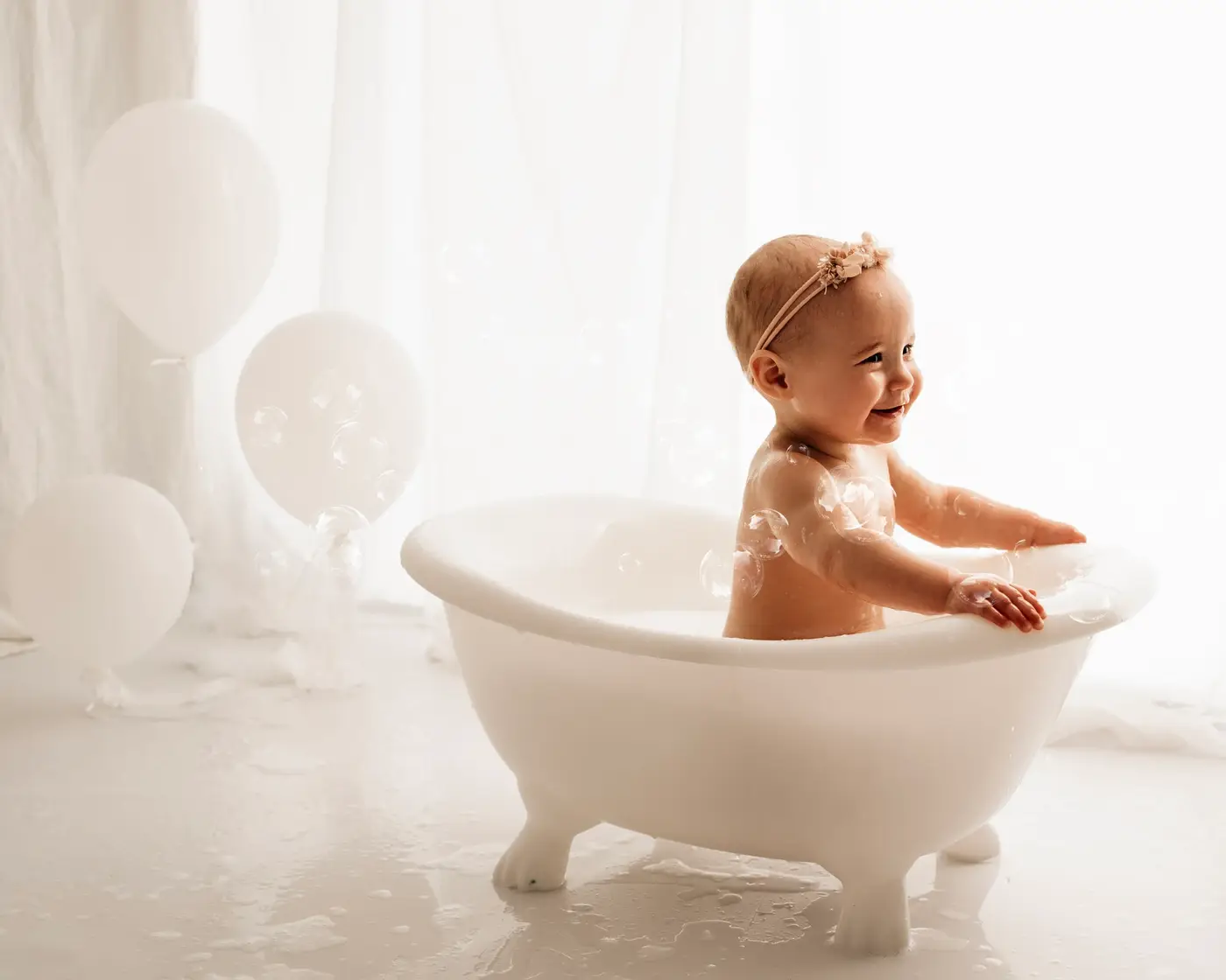smiling baby in a bathtub with balloons during a bradford cake smash photographer photoshoot