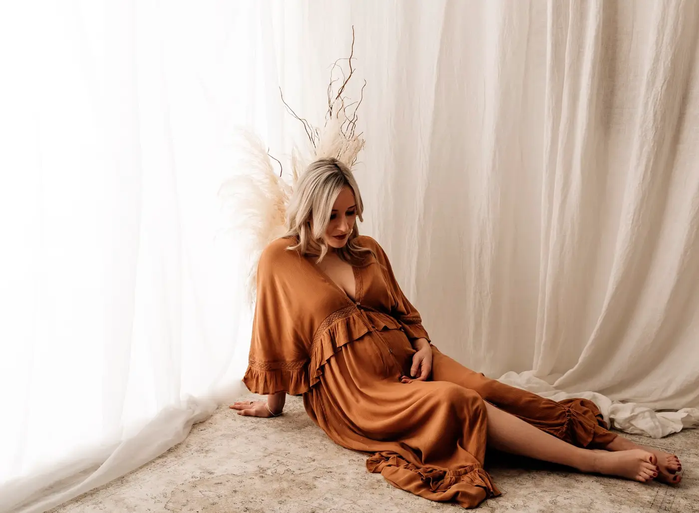 pregnant lady sat down looking at her bump during a cleckheaton maternity photographer photoshoot